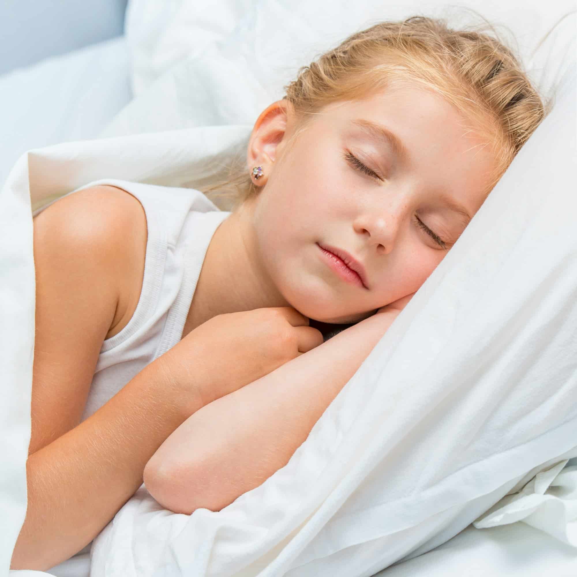 little girl sleeping in white bed