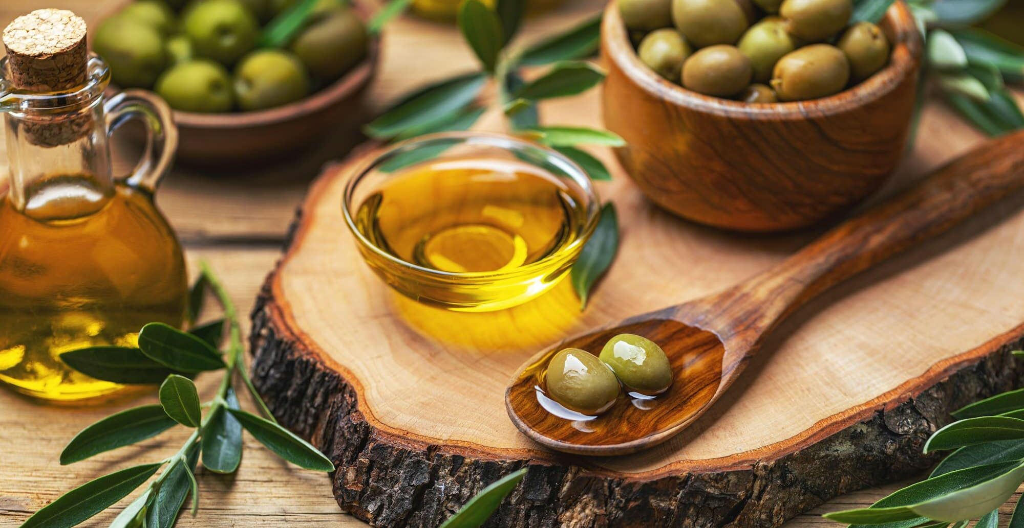Organic olive oil in bowl with green olives