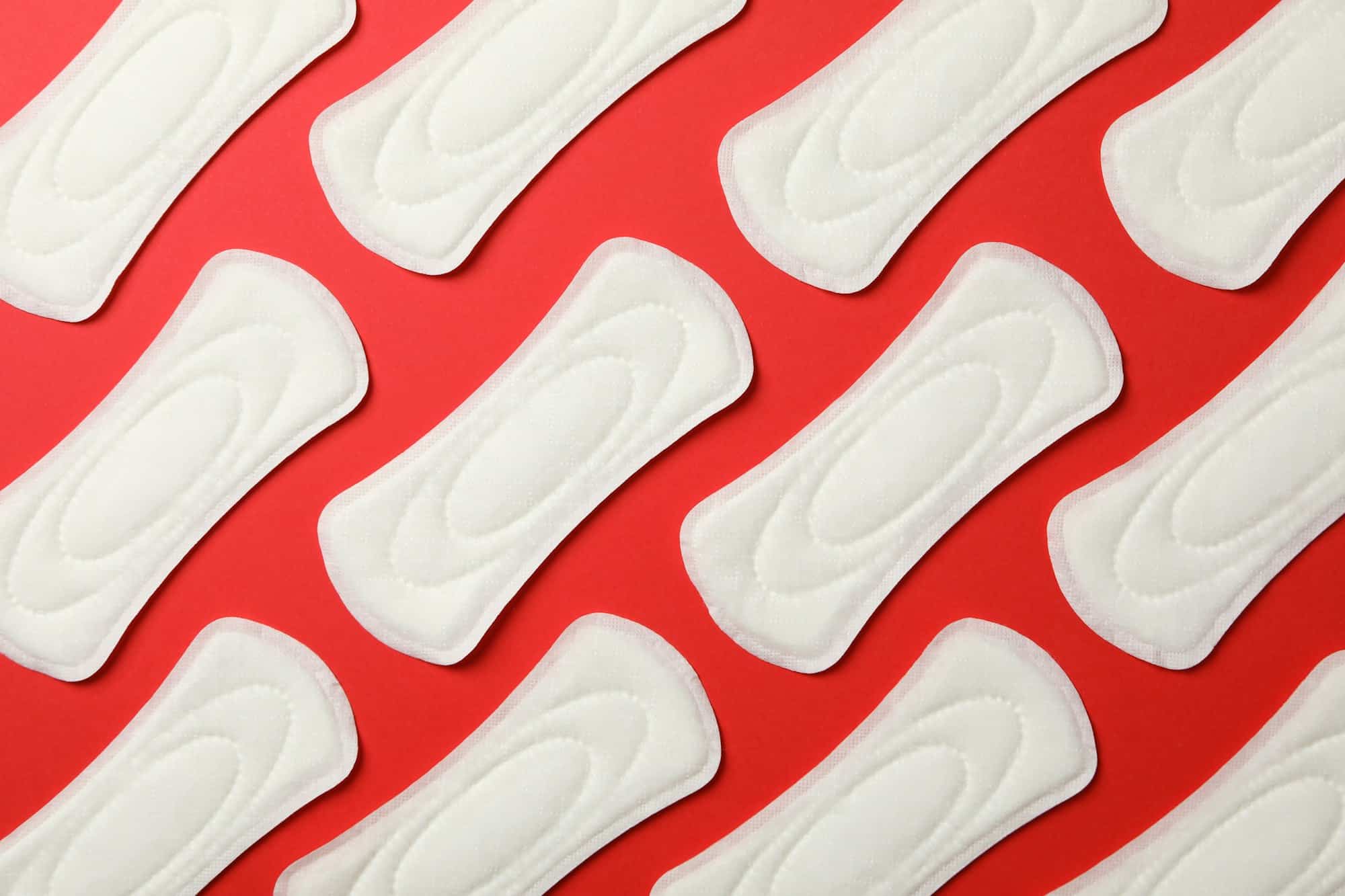Flat lay with sanitary pads on red background, top view
