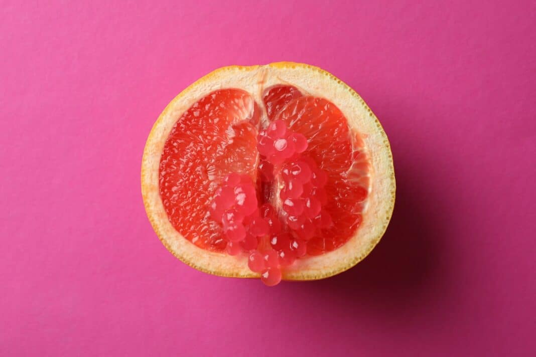 Half of grapefruit with caviar on pink background